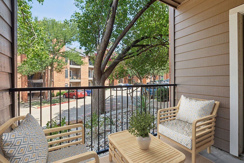 a balcony with a tree and two chairs and a table